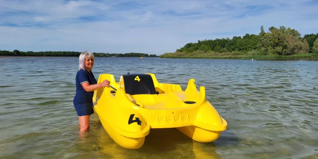 Dame, les jambes dans l'eau près d'un pédalo